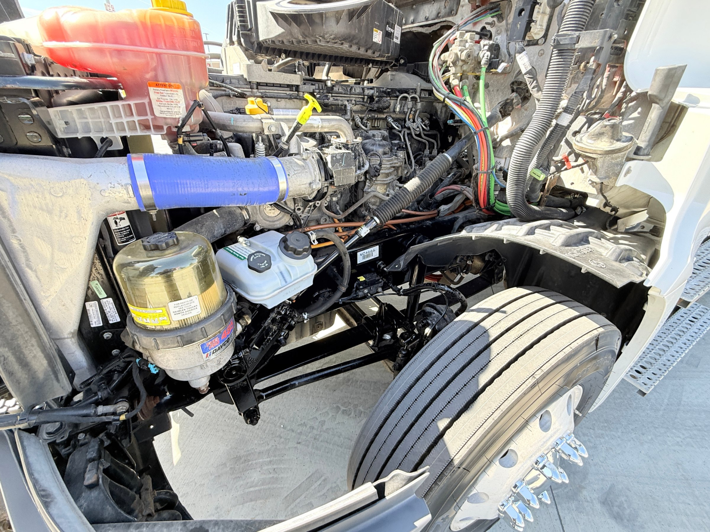 Freightliner PT126064S T engine bay with exposed hoses, wiring, coolant reservoir, and air compressor visible near front wheel.