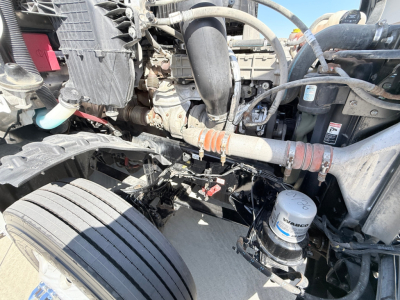 Freightliner PT126064S engine bay showing hoses, belts, air compressor, and coolant reservoir. Visible labels on hoses and filter cap.