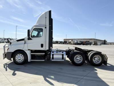 Freightliner PT126064S T conventional daycab truck side view showing cab and chassis with sleeper height behind, fuel tanks, and dual rear axles.