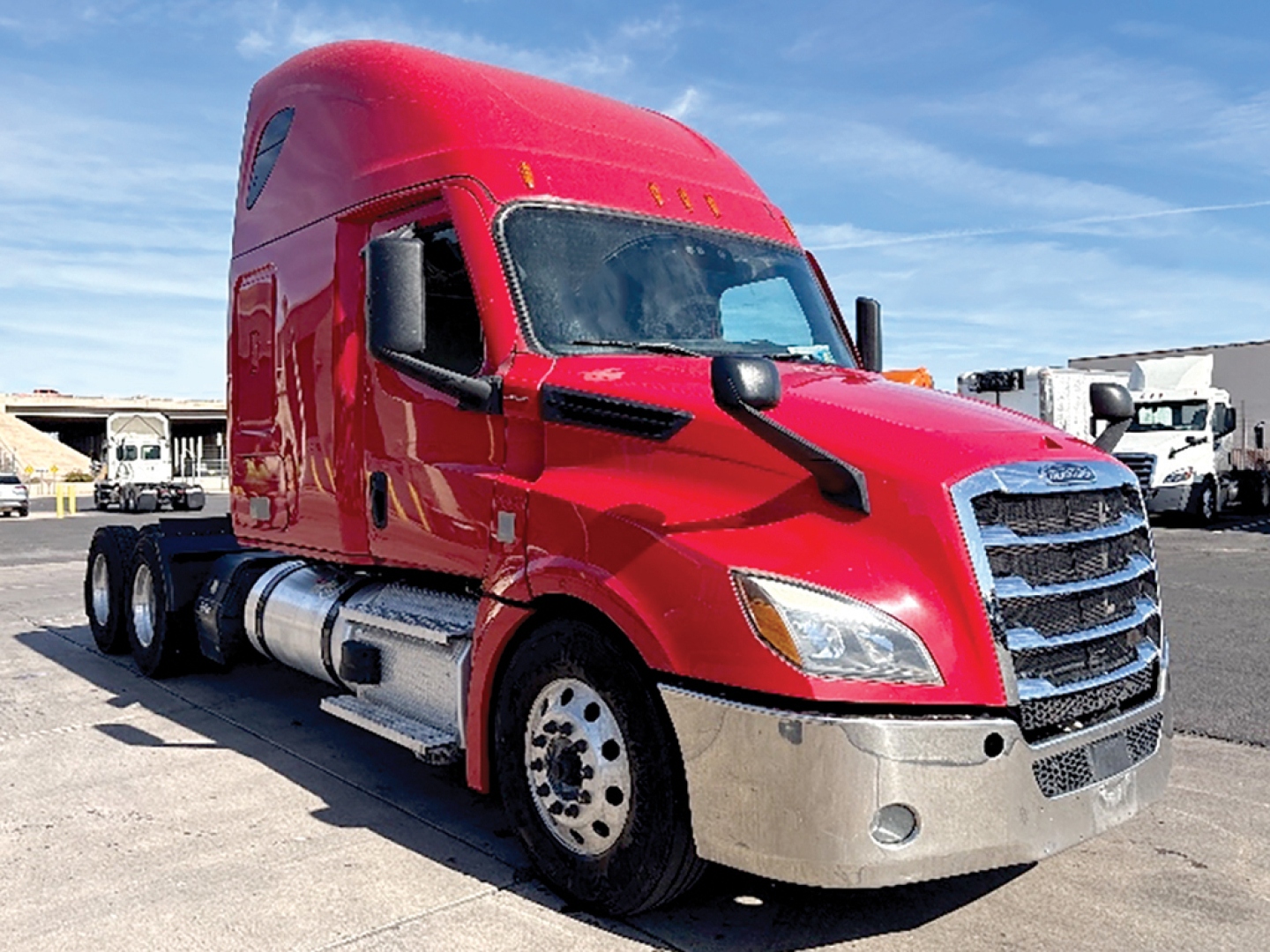 Freightliner Cascadia126 sleeper truck showing red cab and chrome front bumper.