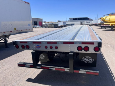 Flatbed trailer deck with rear lights and mud flaps showing Utility logo and trailer components; long aluminum deck, rear bumper, and clearance lights.