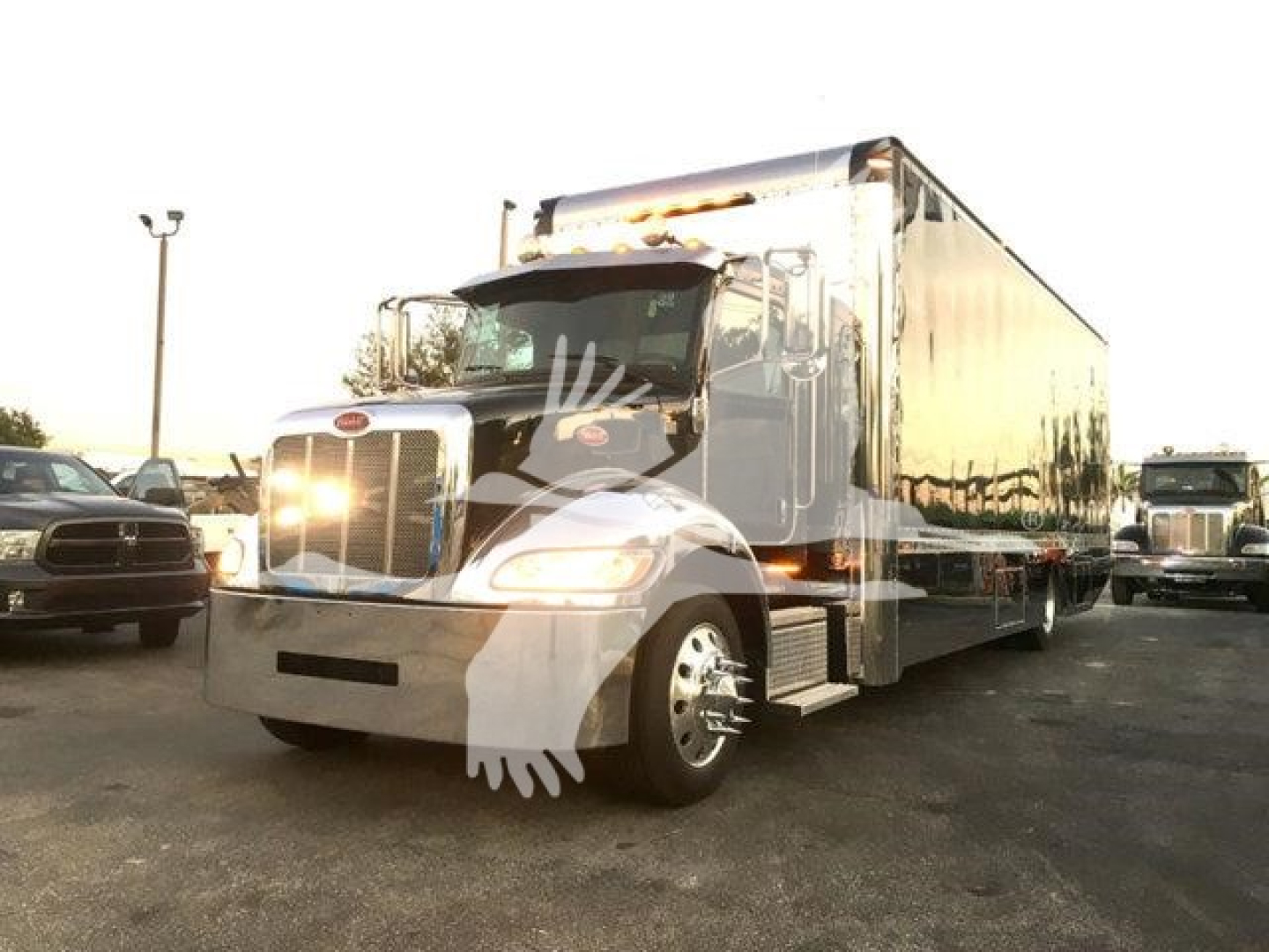 Truck image: 2022 Peterbilt 337 rollback truck with satin chrome trailer, front view showing headlights, grille, and dual rear wheels; stock number J56602 visible in listing context.