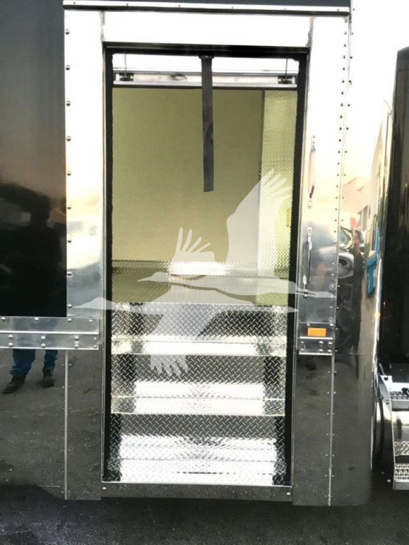 Truck rear view showing metal steps and open doorway of a 2022 Peterbilt 337 rollback truck with diamond plate stairs