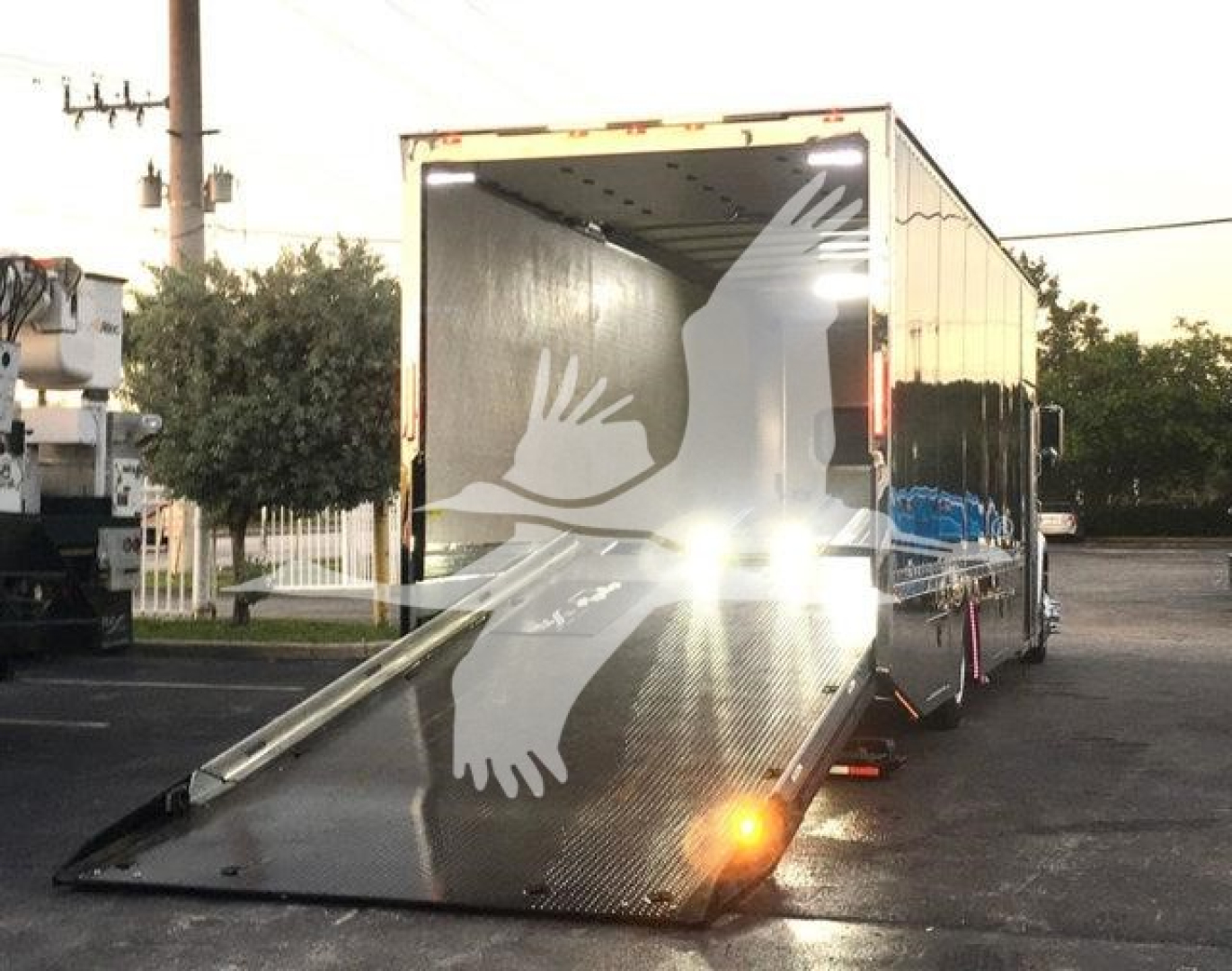 Truck interior/side showing a large empty trailer with fold-down ramp deployed and rear lighting, Peterbilt 337 stock unit in inventory.