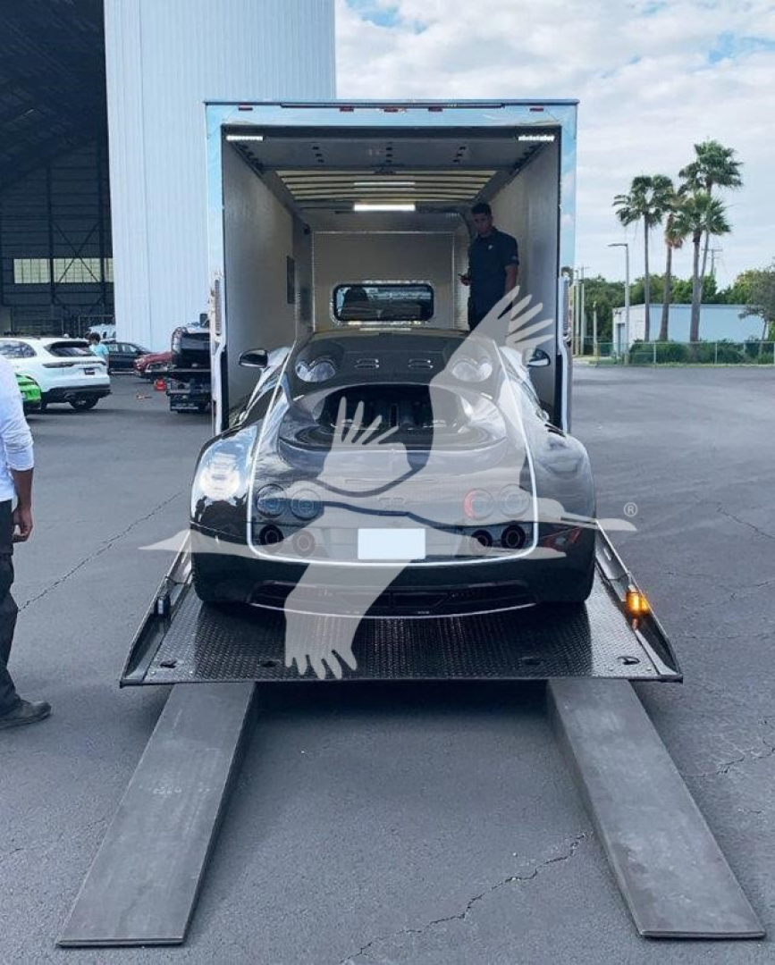 Truck loading into a rollback trailer; rear view of a black Peterbilt 337 inside trailer with loading ramps extended.