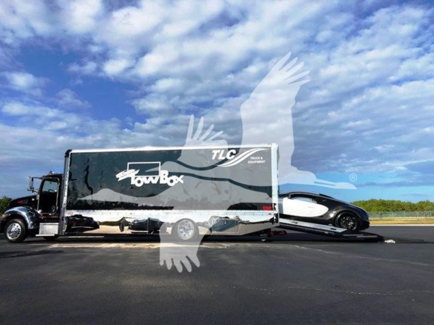 Peterbilt 337 rollback truck with car on tow behind trailer showing TLC TowBox branding and blue sky.