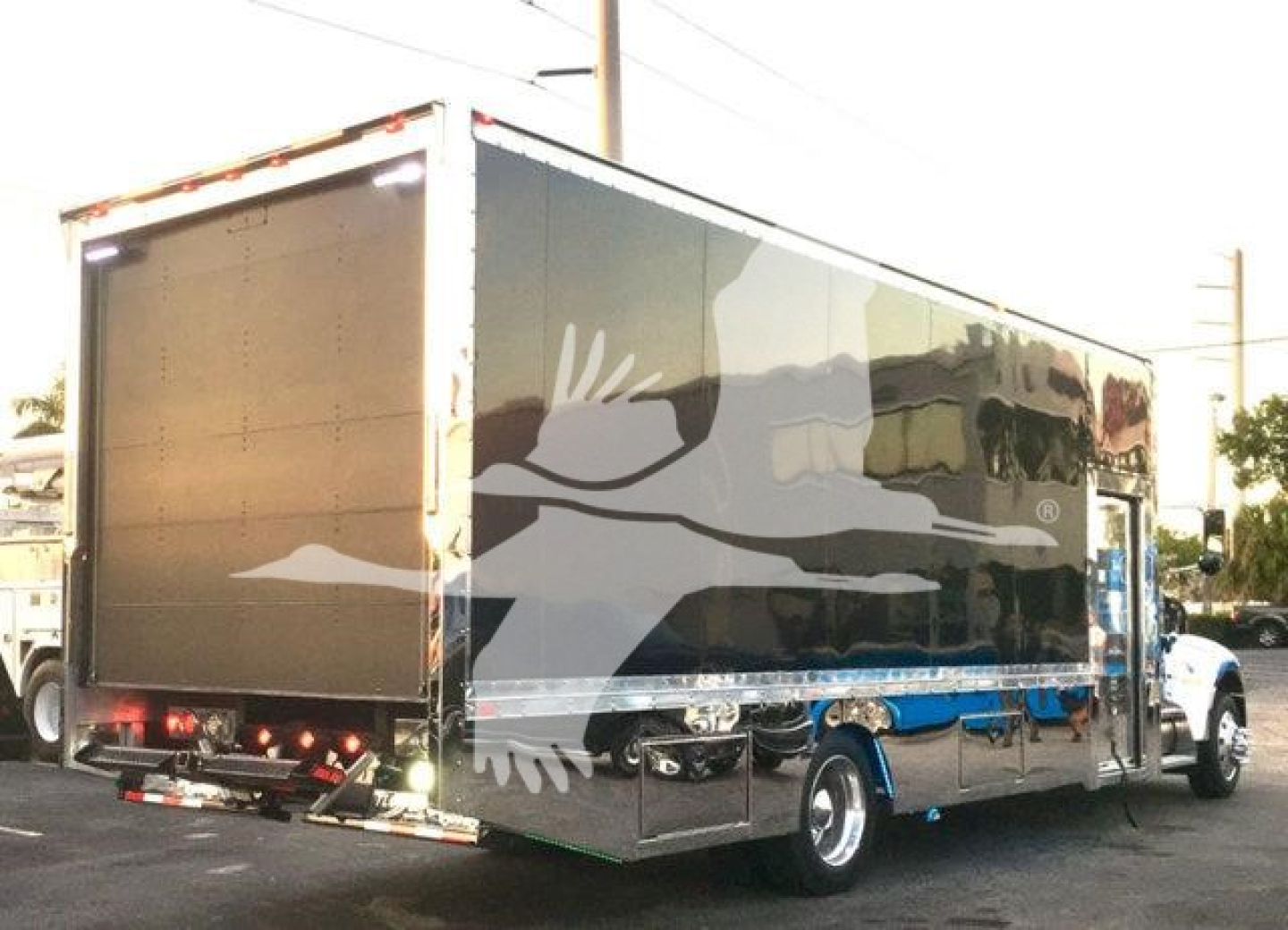 2022 Peterbilt 337 rollback truck, side and rear view showing a large enclosed cargo trailer with dark gray paint and graphic accents.