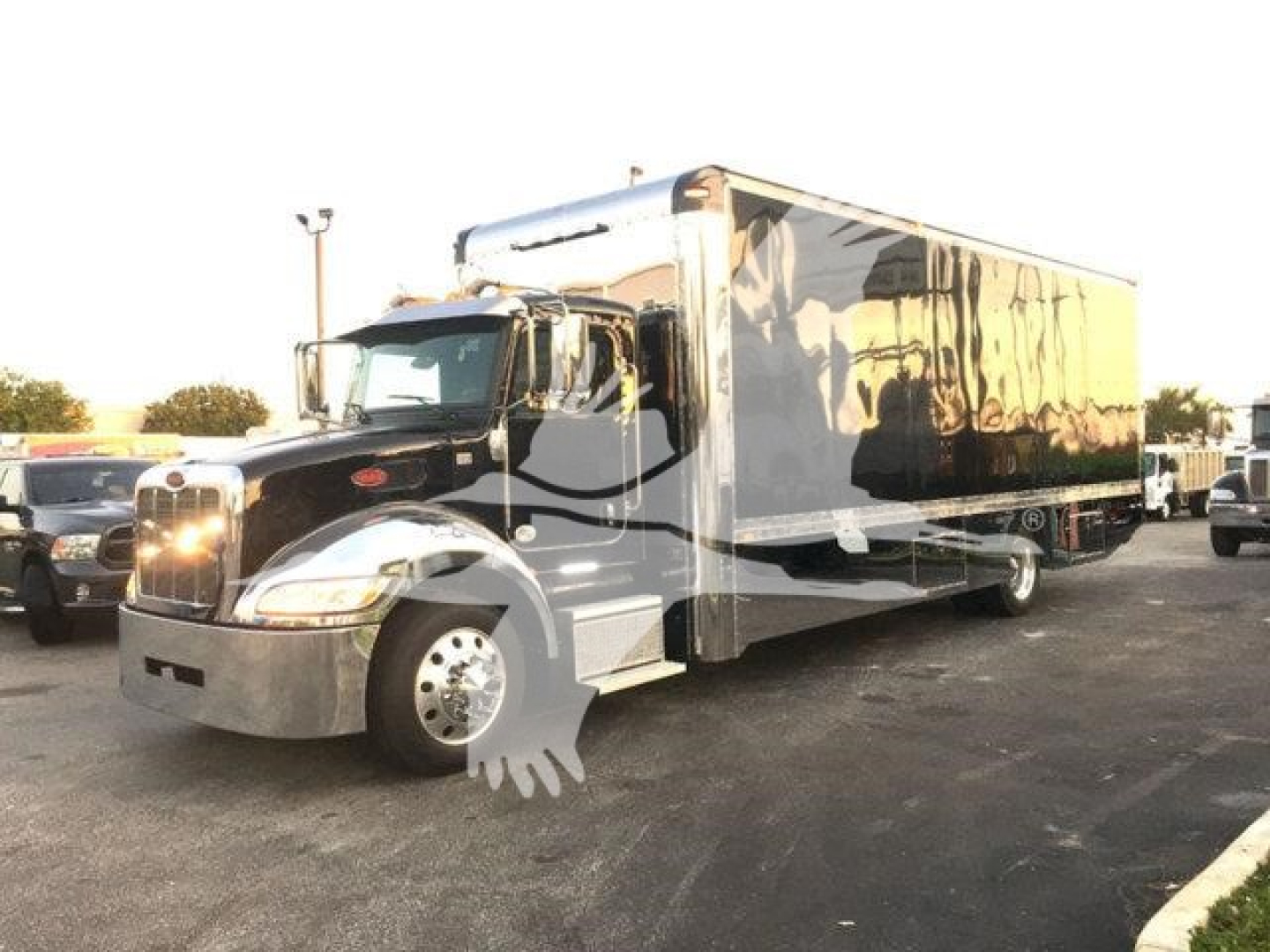 Peterbilt 337 rollback truck with a large chrome bumper and a long black and silver box body, front grille with round headlights.