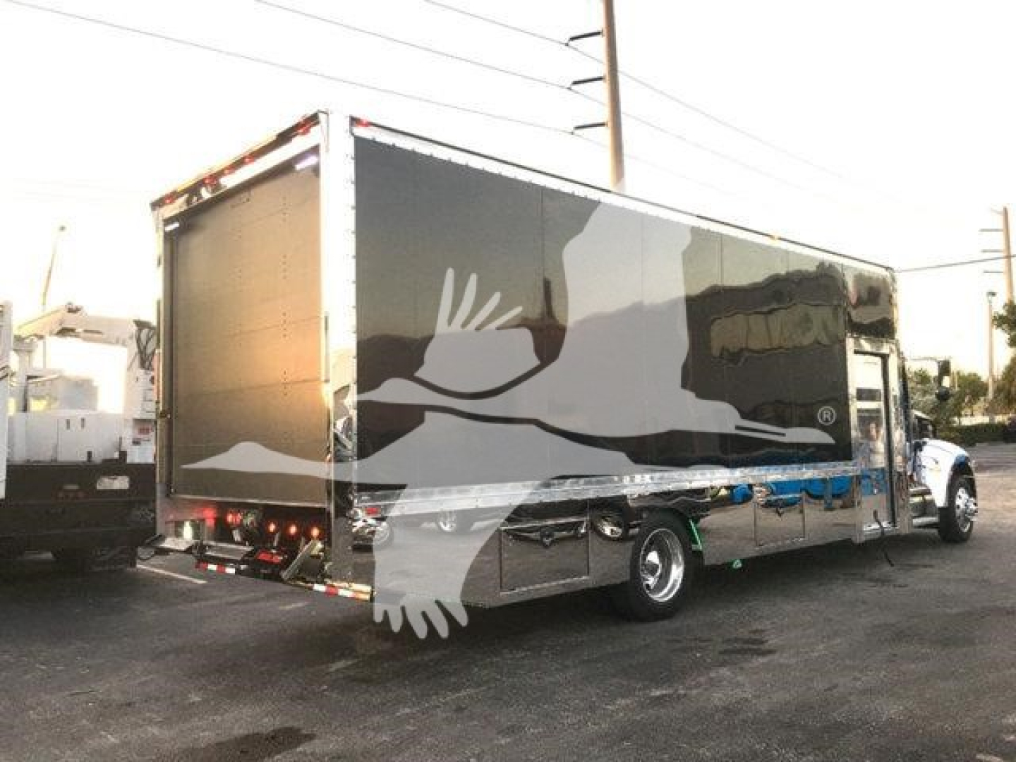 Peterbilt 337 rollback truck with a black cargo box and white graphic design, side and rear view showing the trailer and cab.