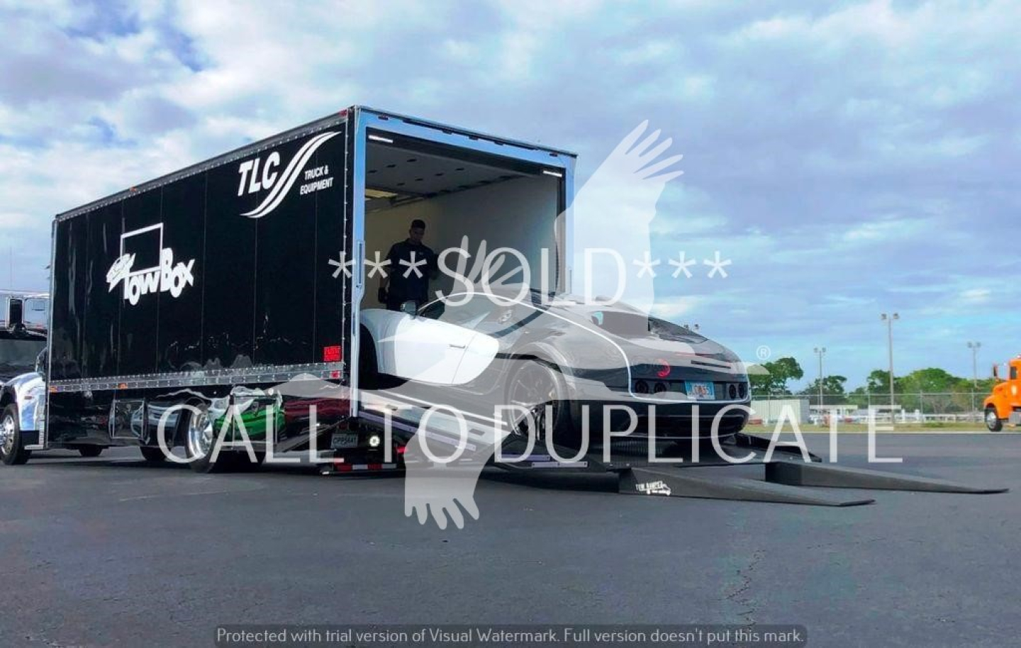 Truck setup showing a black trailer with TLC and logo, connected to a gray Peterbilt 337 rig in rollback configuration.
