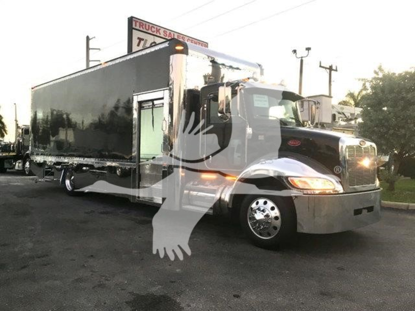 Peterbilt 337 rollback truck in service view showing a large black trailer with chrome front, single cab, and stock number J56602.
