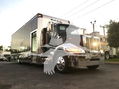 Truck cab and trailer from a 2022 Peterbilt 337 rollback truck showing chrome grille and front wheel