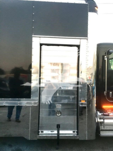 Truck side with a hinged rear door and storage compartment; no legible model text visible.