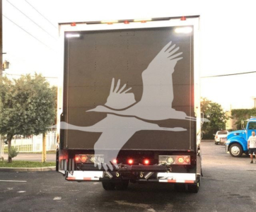 Truck back showing large white geese graphic on black rear doors, with taillights and bumper visible.