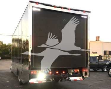 Truck rear showing large graphic of flying geese on a black tailgate; multiple rear lights and reflective strip; no legible text visible