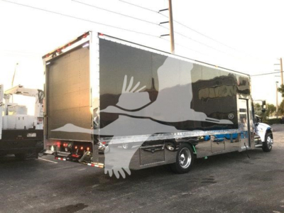 Peterbilt 337 rollback truck with a black cargo box and white graphic design, side and rear view showing the trailer and cab.