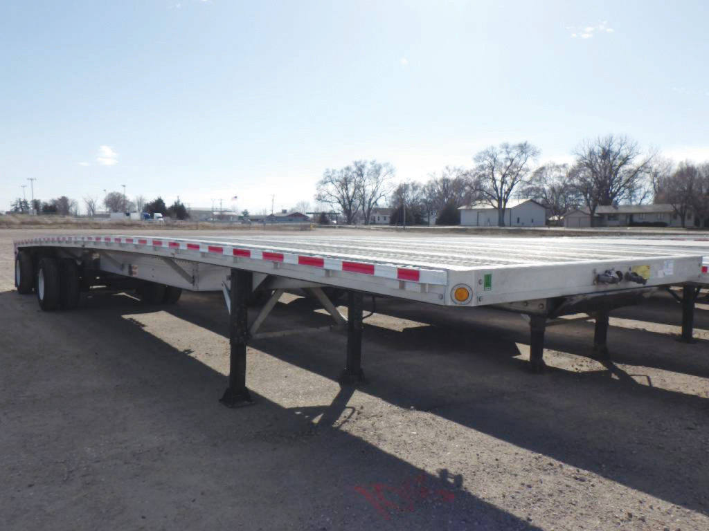Flatbed trailer showing aluminum deck and support legs with reflective tape along edge.