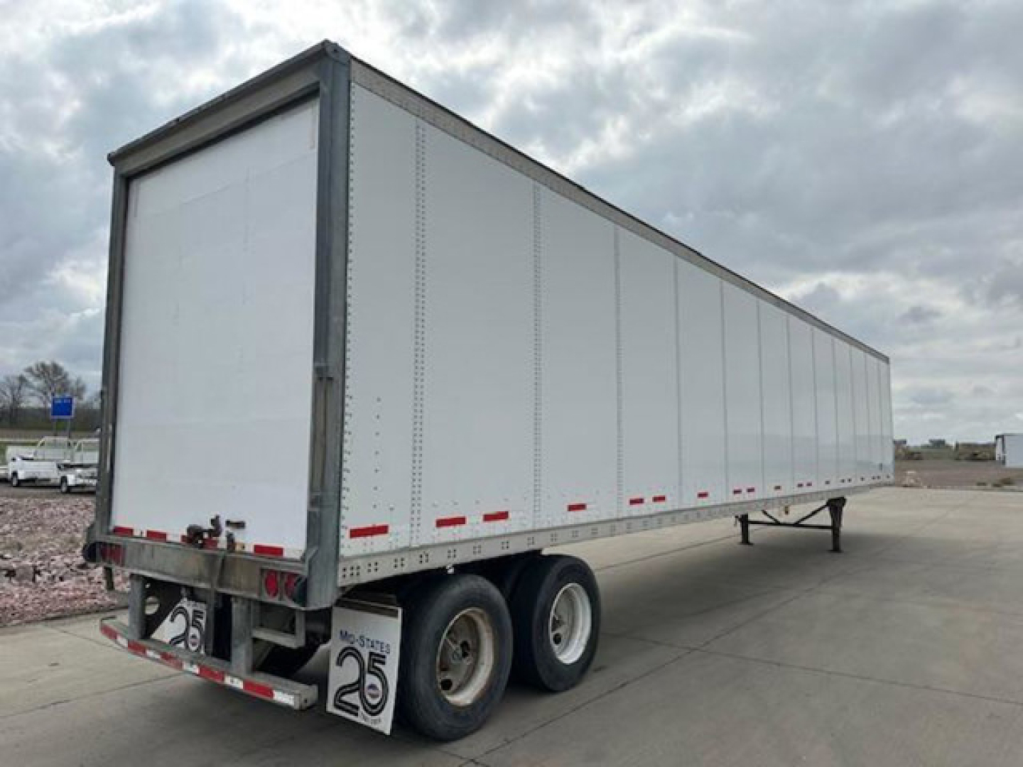 Trailer side view showing a 2013 Wabash van trailer with a white exterior, dual rear axles, and a raised front nose, VIN 1JJV532D4DL786681.