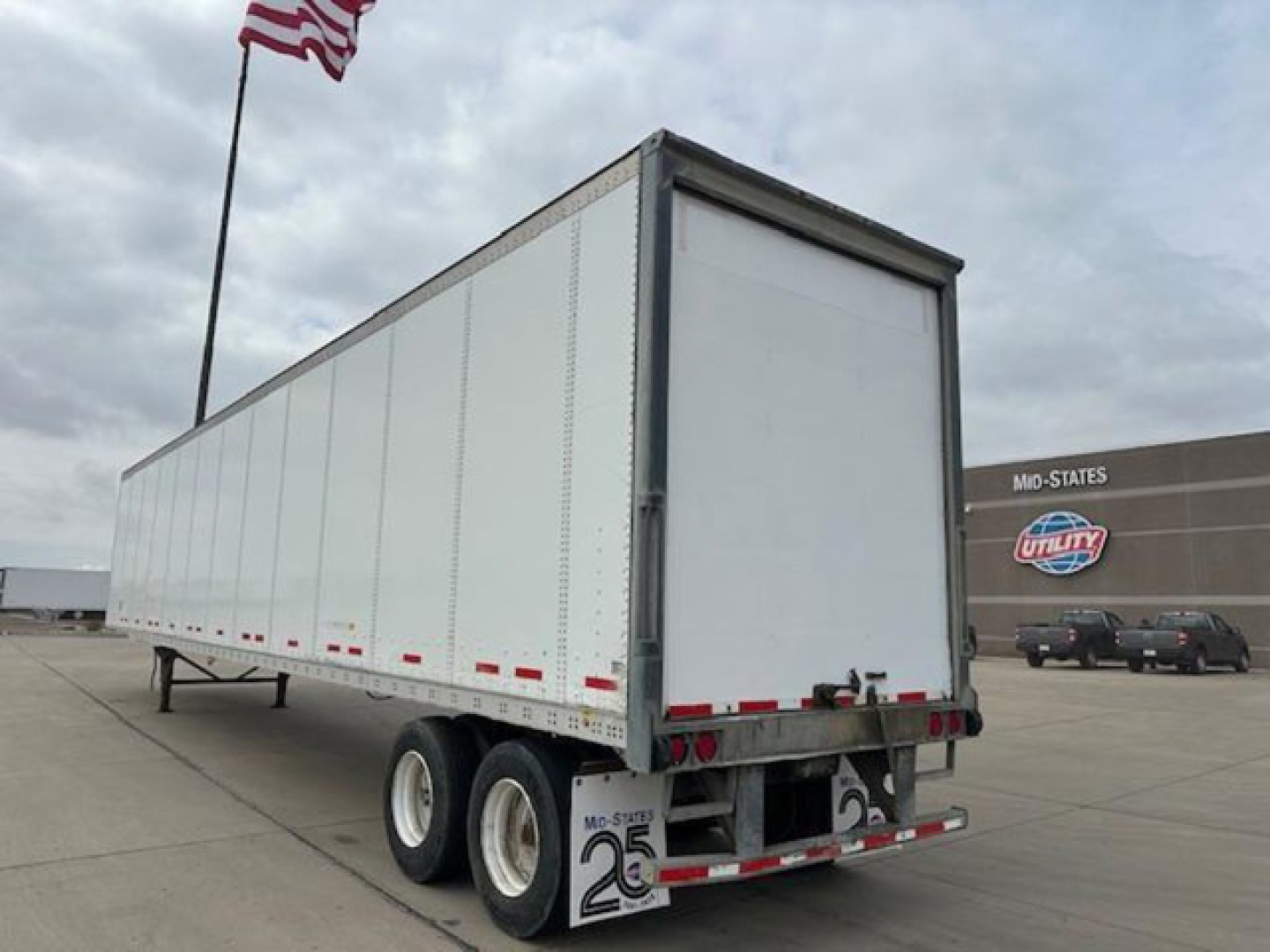 Trailer showing back and side of a 2013 Wabash van with triple-axle tandem wheels and a rear roll-up door.