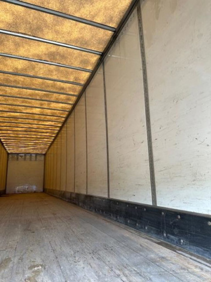Van trailer interior showing empty cargo area with side walls and ceiling beams.