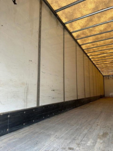 Trailer interior showing empty cargo bay with white sidewalls, black lower trim, and ribbed ceiling. No visible model text or numbers inside.