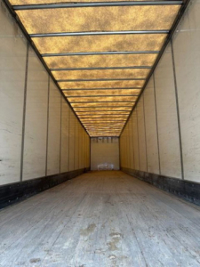 Trailer interior showing long empty Wabash van trailer with wooden ceiling panels and side walls, empty cargo floor.