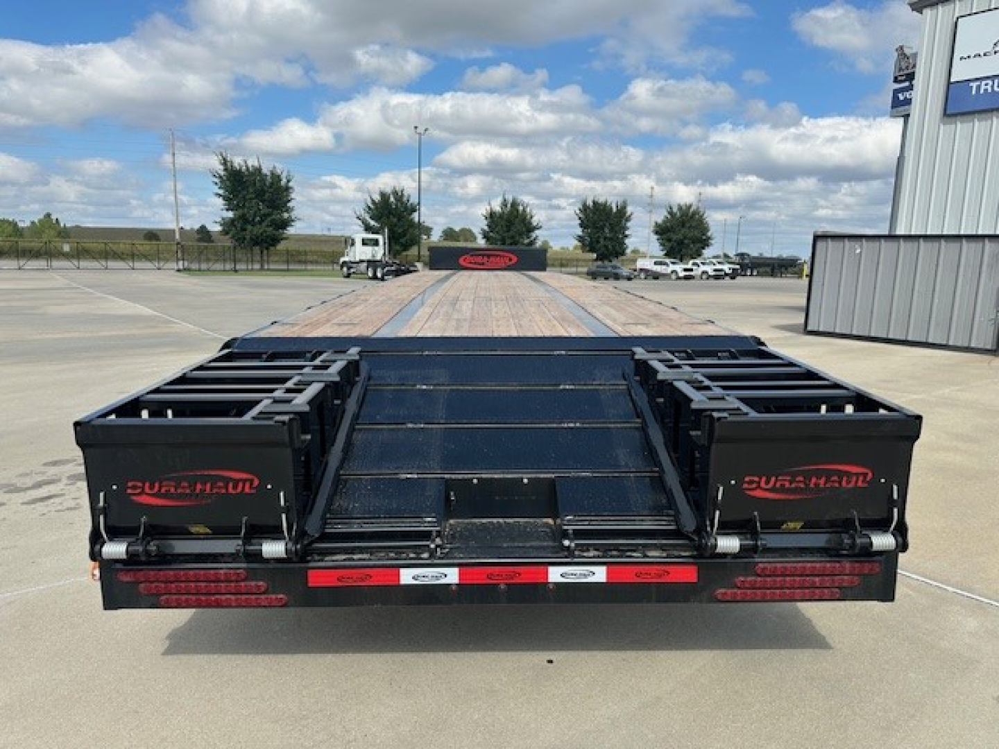Dura Haul drop deck trailer rear view showing spread tail ramps and black toolbox compartments on a 53' trailer.