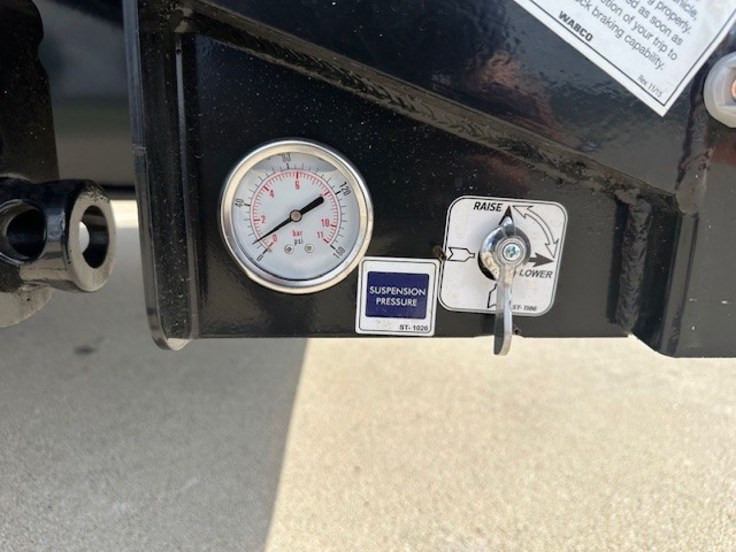 Trailer gauge panel showing a round pressure gauge and a suspension pressure label with a small lever and label reading SUSPENSION PRESSURE.