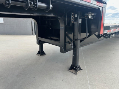 Trailer hitch area showing landing gear and undercarriage of a 2027 Dura Haul drop deck trailer with spread tail ramps, black steel frame, and stabilizer legs.