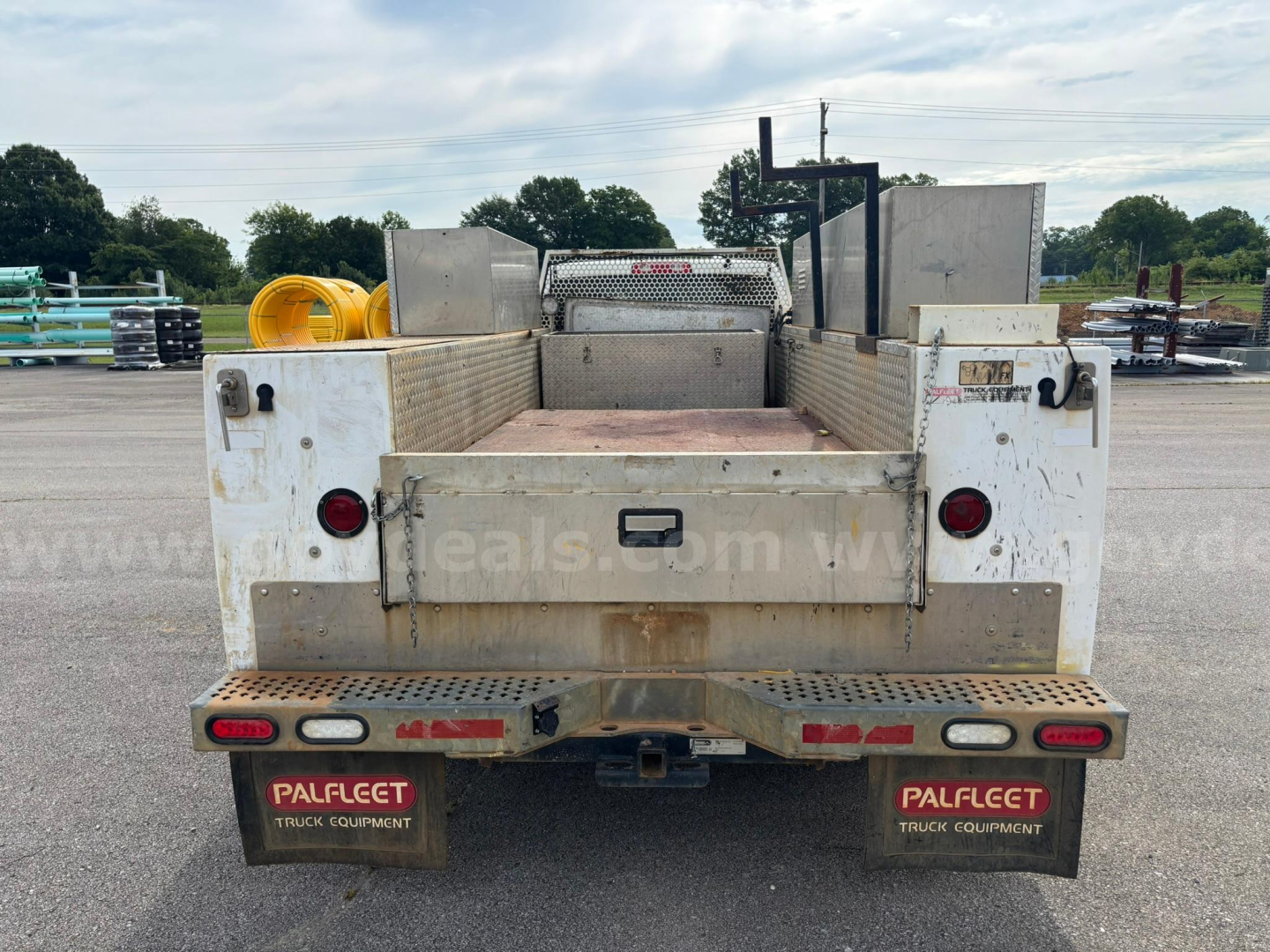 Rear view of a 2012 Dodge Ram 5500 service truck showing flatbed with steel diamond plate, tail lights, and Pallet logo mud flaps.