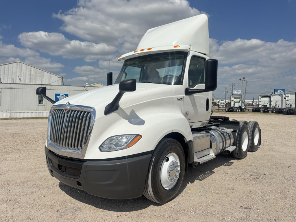 Truck cab with white International LT 6x4 tractor showing grille and side mirrors.