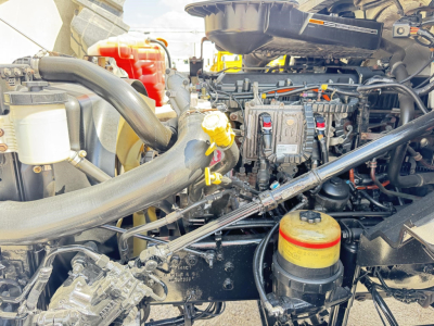 Engine bay view of a 2019 International LT truck showing yellow-capped fluid reservoirs and multiple hoses and components.