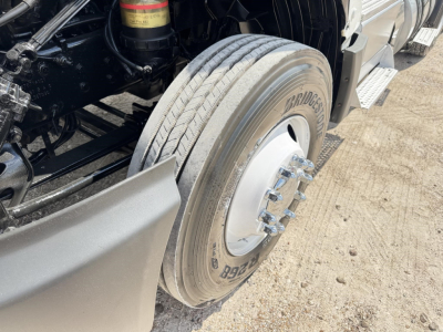 Truck front wheel close-up showing Bridgestone tire and wheel, part of a 2019 International LT conventional daycab underbody components visible.