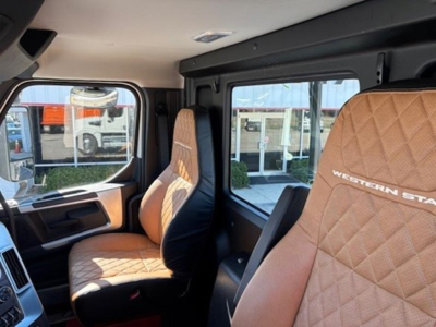 Truck cab interior with tan diamond-stitched seats; driver and passenger seats visible with 'WESTERN STAR' branding on headrests. Side window and door area visible.