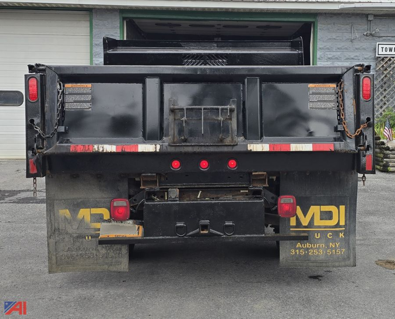 Ford F-450 dump truck rear view showing plow underbed and taillights, with MDI? branding and contact text on mudflaps.