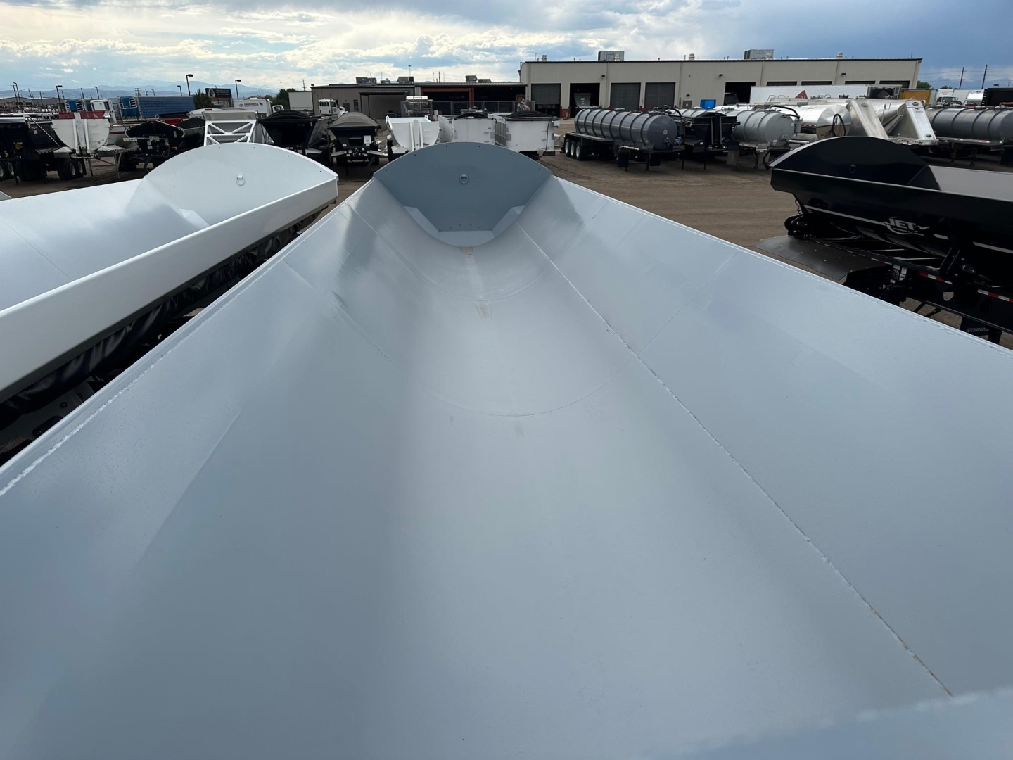 Trailer top view of a 40' Jet air ride side dump with smooth silver metallic surface and electric tarp system, showing high side walls and peak center.