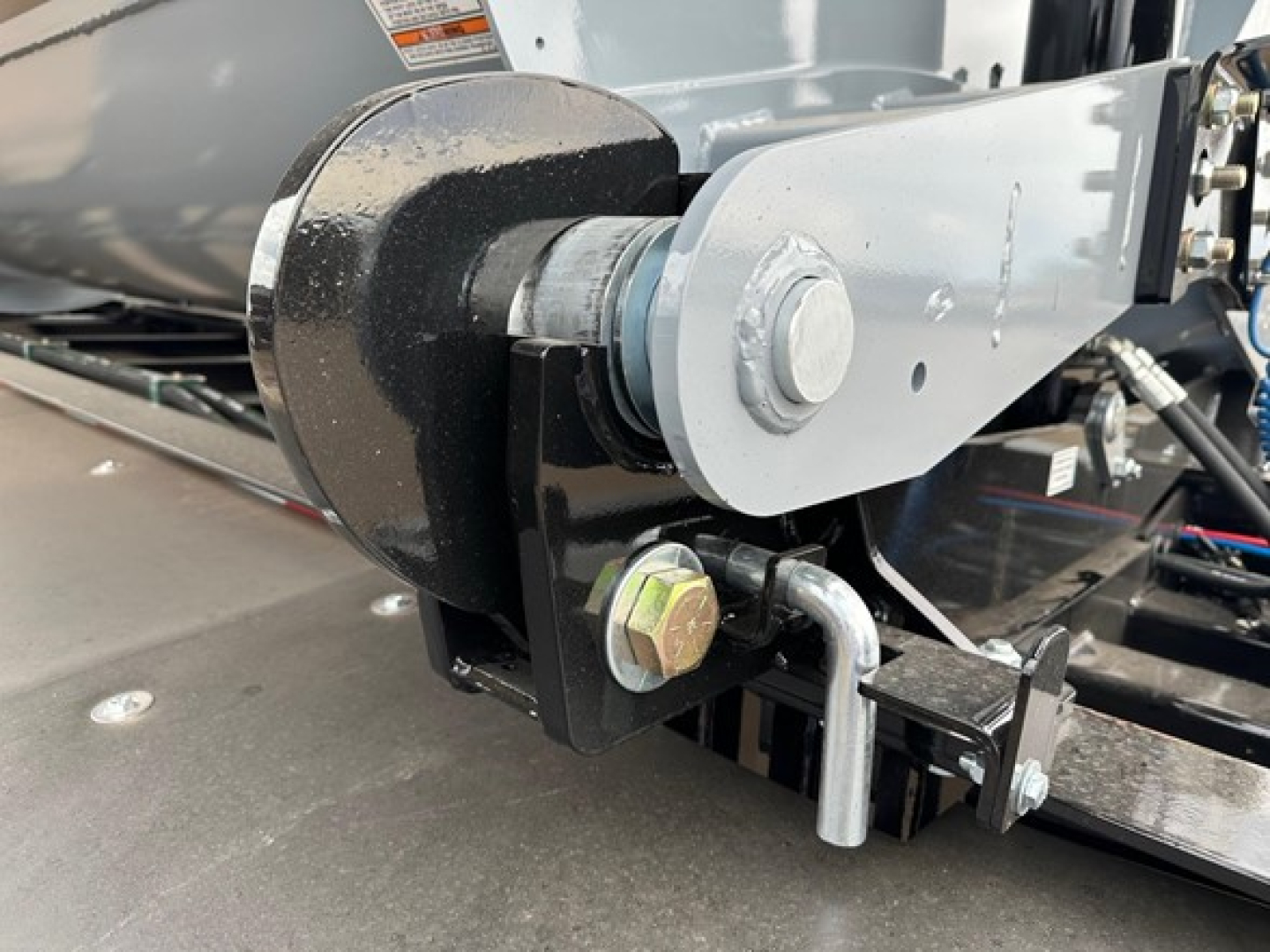 Trailer hitch mechanism and side dump components on a jet air ride trailer showing a wheel hub, mounting bracket, bolt, and hydraulic linkage.