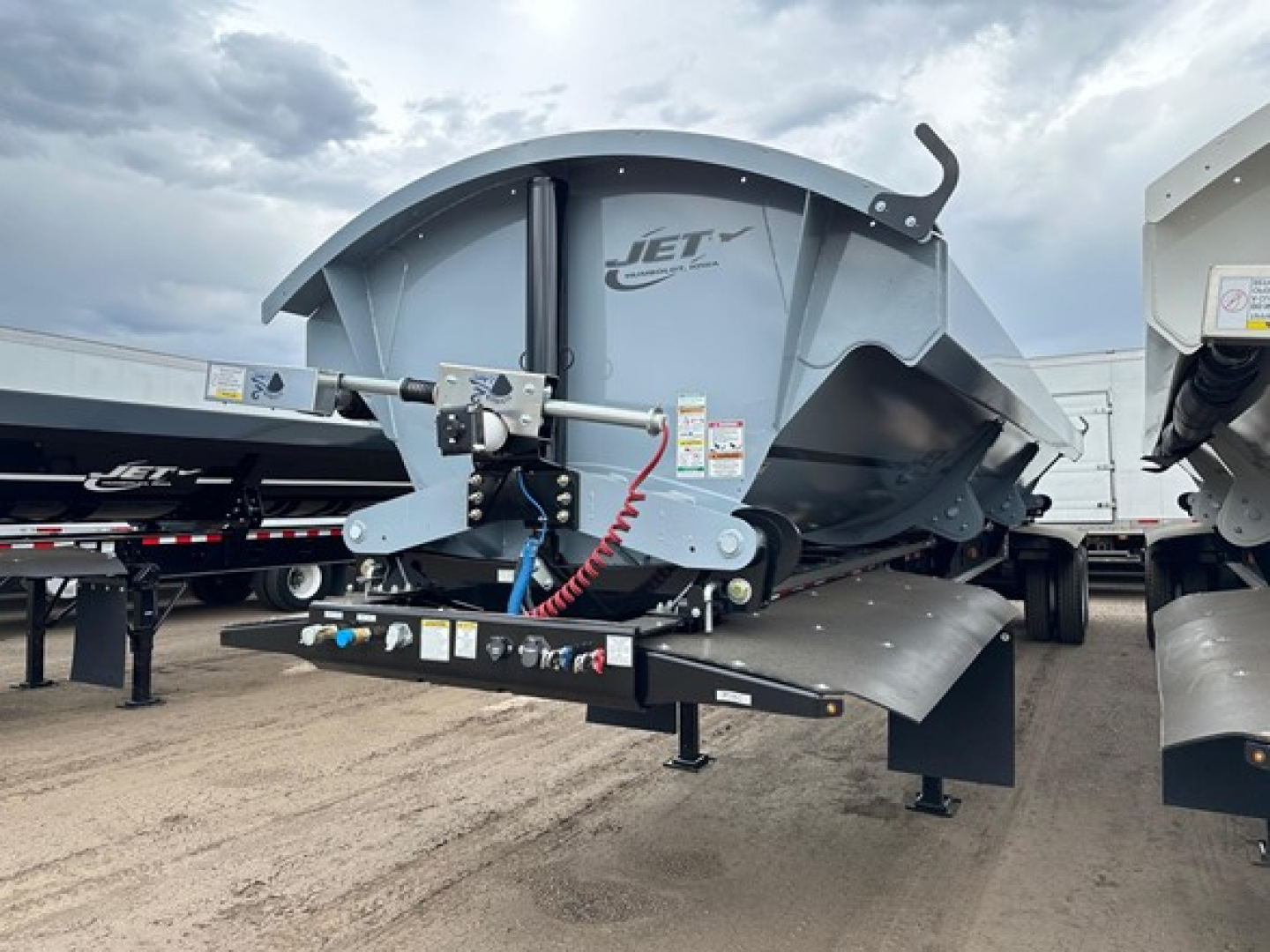 Jet air ride side dump trailer showing front-left view with hydraulic hoses and support frame, Jet logo on body, blue-gray paint.