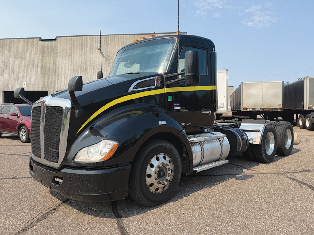 Kenworth T680 truck in black with yellow stripe, front-left view showing sleeper cab, chrome exhaust stack, and dual rear axles.