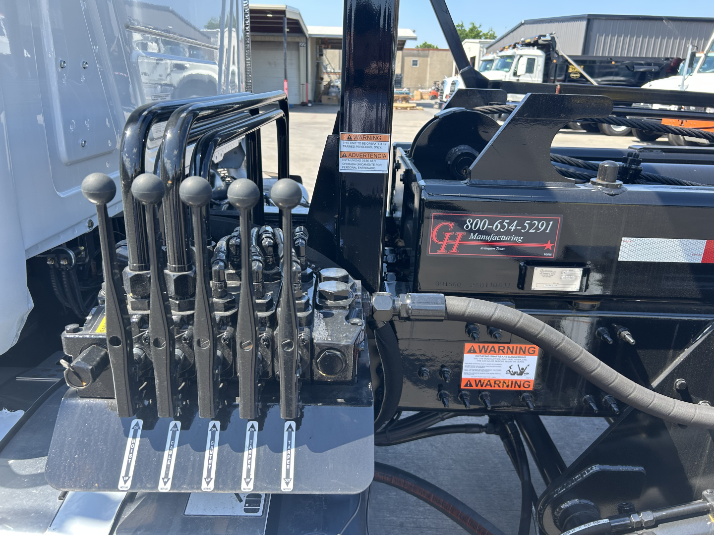 Levers and hydraulic controls on a 2026 Mack GR64B roll-off truck with control levers and hydraulic lines visible.