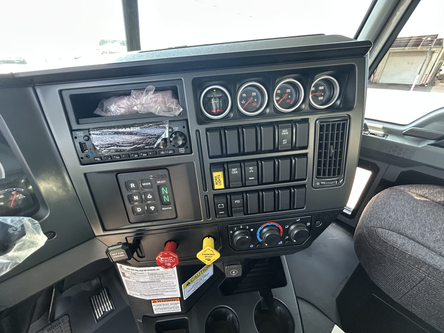 Dashboard of a 2026 Mack GR64B roll-off truck showing instrument gauges, control switches, and an open slot for radio/climate controls.