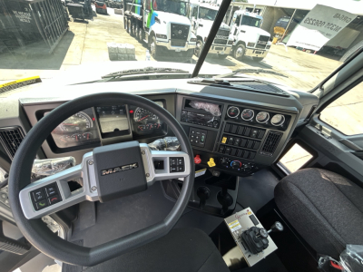 2026 Mack GR64B interior cockpit view showing steering wheel, dashboard with gauges, center console, and gear selector. Text on steering wheel reads 'MACK'. Various control panels and displays are visible.