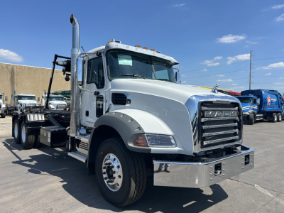Truck cab with gray Mack GR64B front view showing chrome bumper, grille, and dual exhaust stack.