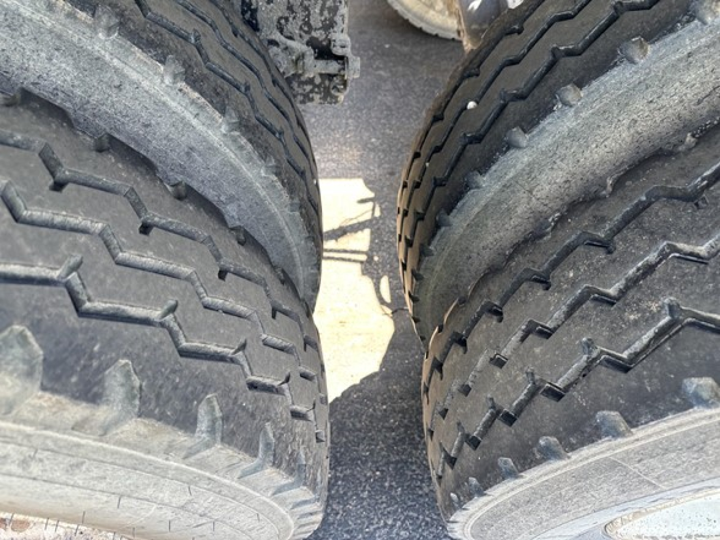 Dump trailer wheel area showing dual tires with tread pattern and some dirt