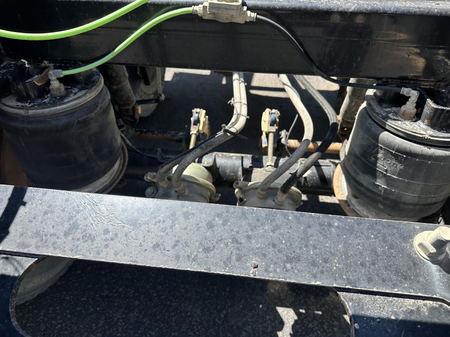 Trailer underside showing air ride components and hydraulic lines with tanks and fittings.