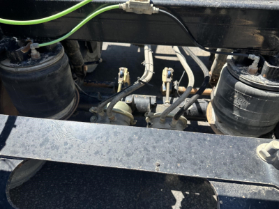 Trailer underside showing air ride components and hydraulic lines with tanks and fittings.