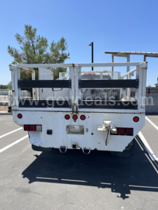 Truck bed of a 2015 Chevrolet Silverado 2500HD flatbed dump showing rear view with metal cargo gates and tail lights.