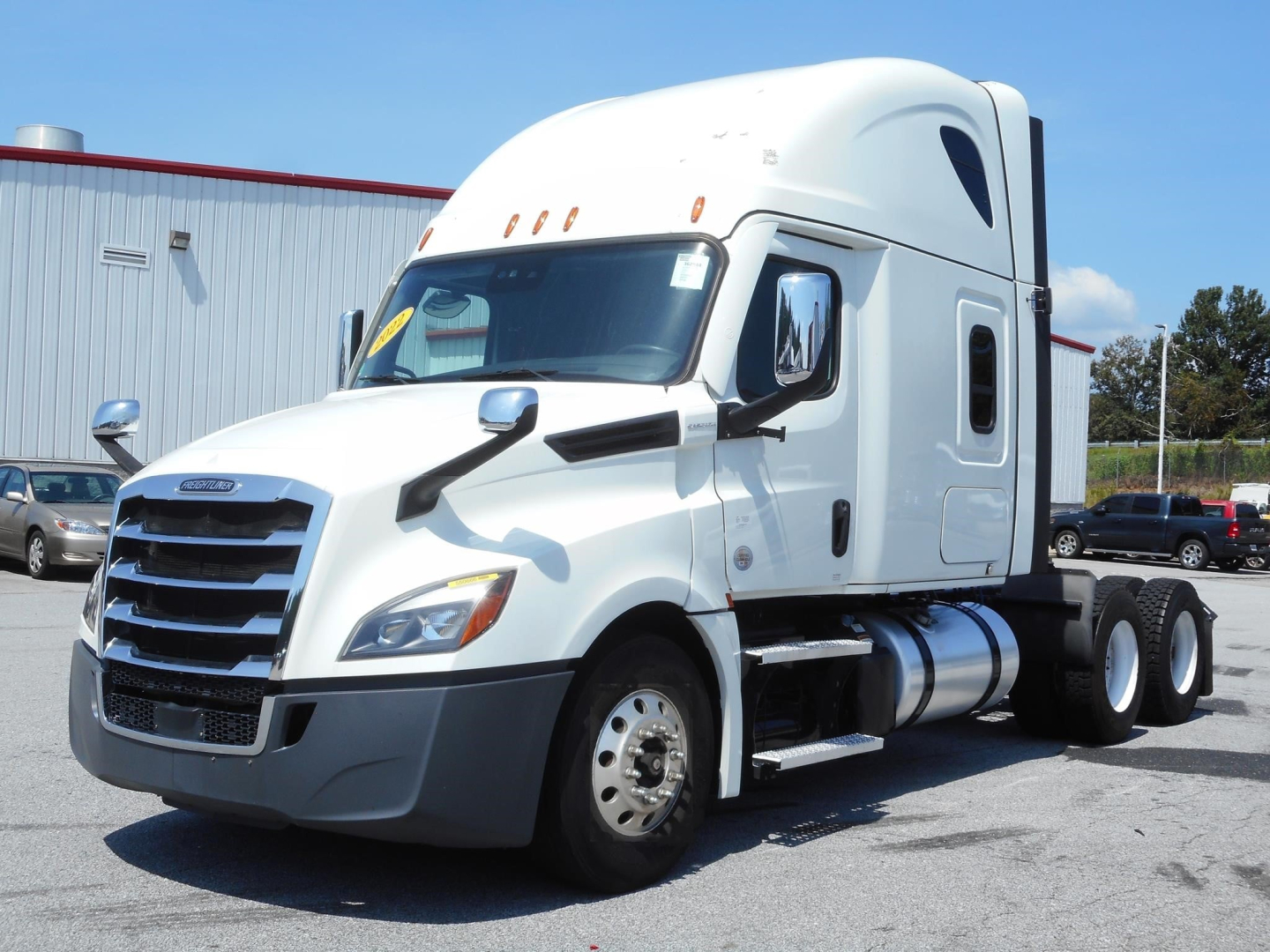 Truck engine bay area showing Freightliner Cascadia 126 sleeper cab with large grille and dual rear axles.