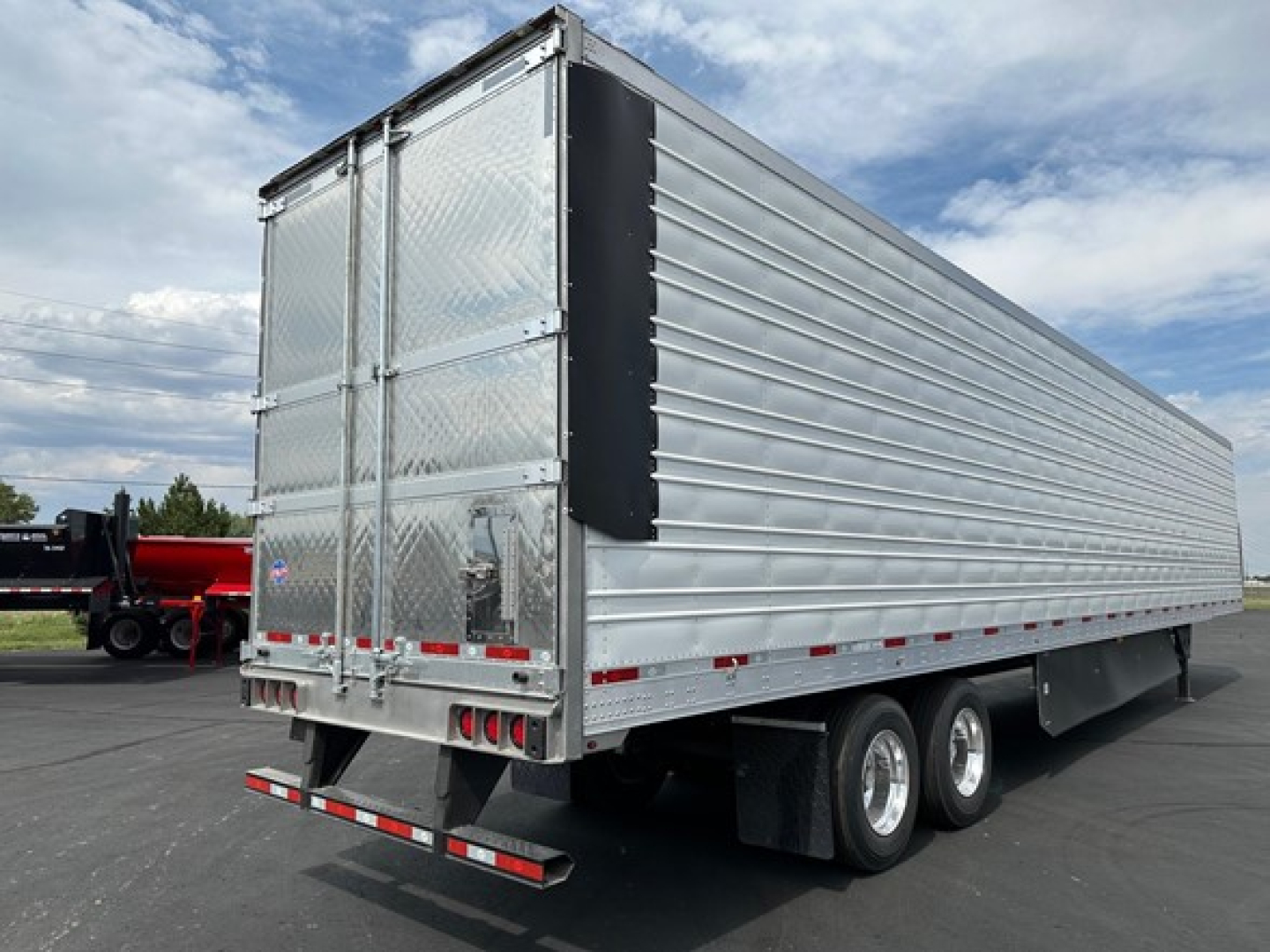 Trailer side and rear showing utility cargo trailer with aluminum corrugated walls, dual rear doors, and tandem axles.