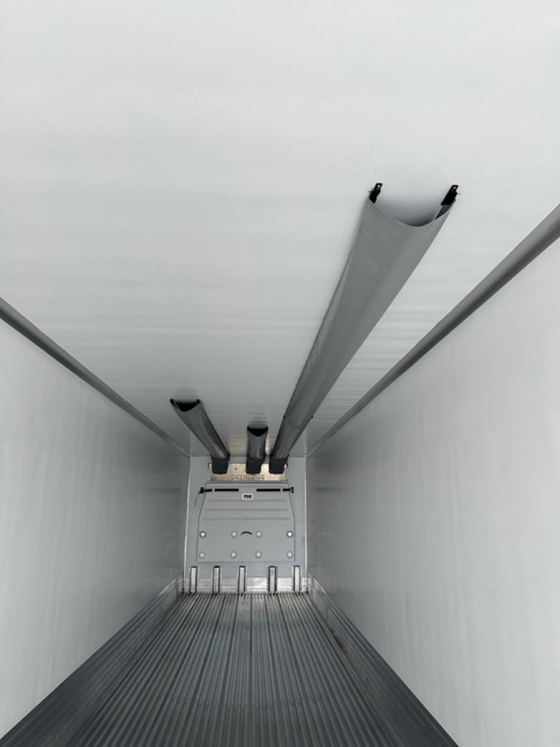 Trailer interior showing reefer cargo trailer with ribbed floor and side walls, rear door area, and ceiling supports.